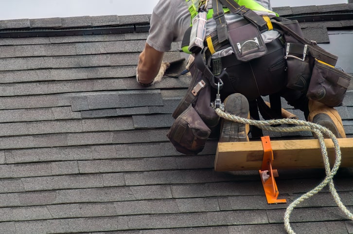 Roof Construction Worker Ensuring Roof Maintenance with Security Rope